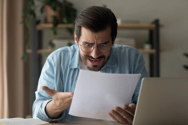 Zenuwachtige jongeman lees absurde lening voorwaarden voorgesteld door de bank — Stockfoto