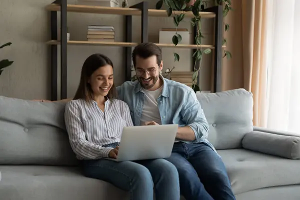 Young family couple sit by laptop discuss flat renovation options