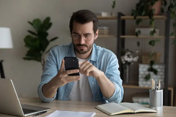 Serious young guy student check uncertain information online using smartphone — Stock Photo, Image