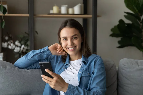 Snygg ung kvinna njuta av fritid hemma med hjälp av telefon — Stockfoto