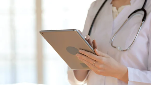 Närbild ung kvinnlig läkare med hjälp av digital dator gadget. — Stockfoto
