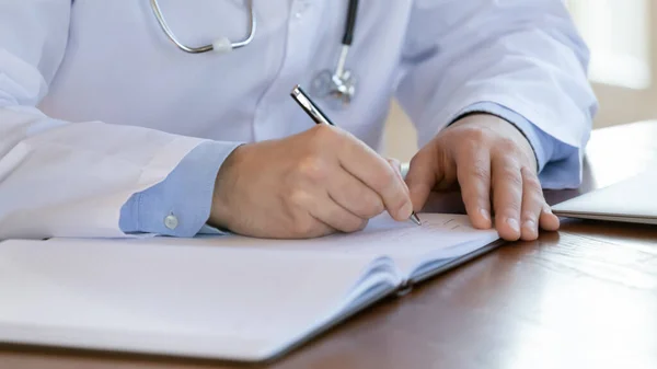 Közelkép férfi orvos írás jegyzetek regiszter könyv. — Stock Fotó