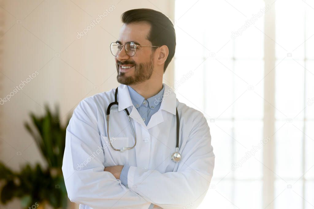 Smiling young handsome professional male doctor looking in distance.