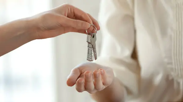 Primer plano joven agente inmobiliario femenino dando llaves a comprador feliz. — Foto de Stock