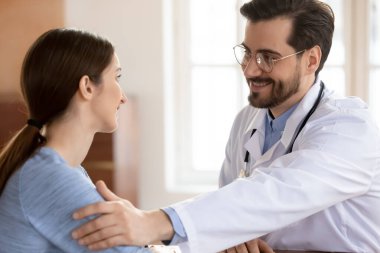 Gülümseyen 35 'lik erkek doktor hastaya iyi haberler veriyor..