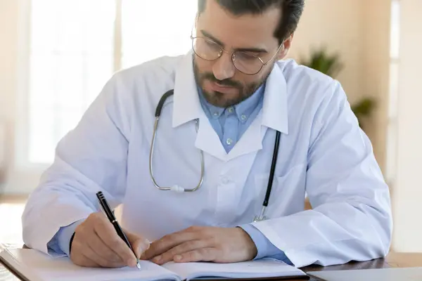 Skickliga läkare skriva anteckningar i registret bok. — Stockfoto