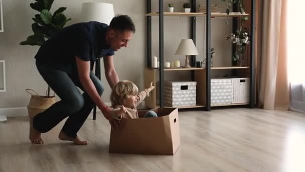 Happy aimant jeune père poussant boîte en carton avec petit enfant. — Video