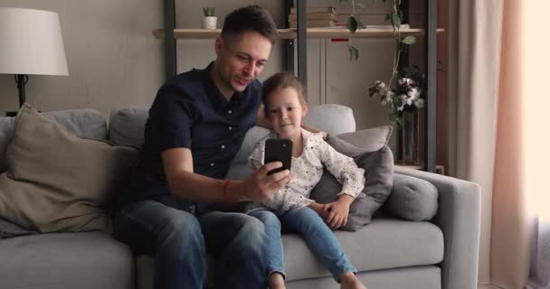 Glad liten söt flicka med hjälp av roliga mobilappar med pappa. — Stockvideo