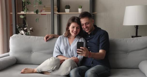 Boldog fiatal szerető család pár okostelefon használata. — Stock videók