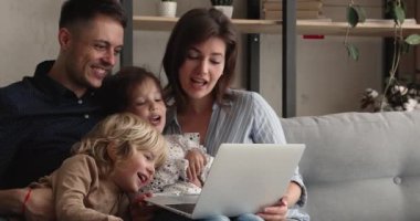 Mutlu, genç, rahat ebeveynler çocuklarla çizgi film izliyor..