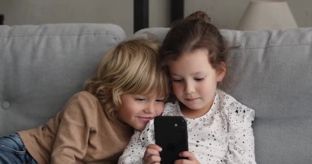 Bedårande liten förskola pojke och flicka spelar mobila spel. — Stockvideo