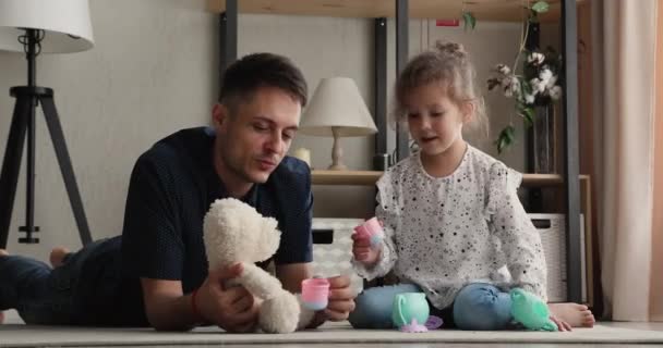 Vreugdevolle jonge vader spelen speelgoed met schattige baby dochter. — Stockvideo