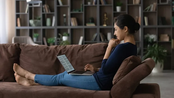 Jovem mulher indiana relaxar no sofá trabalhando no laptop — Fotografia de Stock