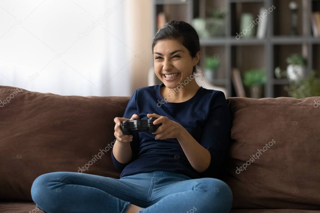 Happy Indian female gamer play video game at home