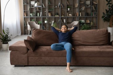 Mutlu Hintli kadın modern evdeki kanepede dinleniyor.