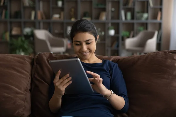 Happy Indian woman use tablet texting online