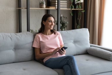 Gülümseyen Hintli kadın modern telefon kullanarak hafta sonunu evde geçiriyor.