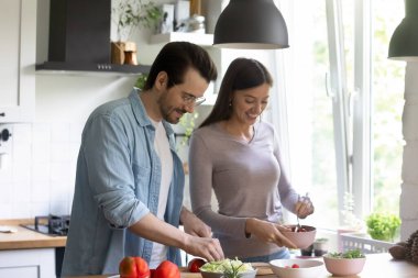 Mutlu milenyum çifti mutfakta sağlıklı salata pişirir.