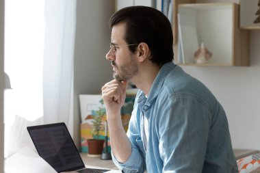 Düşünceli adam bilgisayarda çalışıyor. Mesafeli düşünüyor.