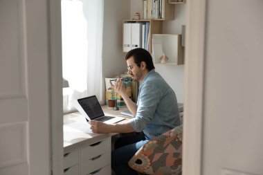 Hoparlörden konuşan genç adam bilgisayarla çalışan akıllı telefondan konuşuyor.