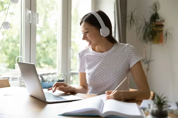 Χαμογελώντας φοιτήτρια σε ακουστικά μελέτη σε απευθείας σύνδεση στον υπολογιστή — Φωτογραφία Αρχείου