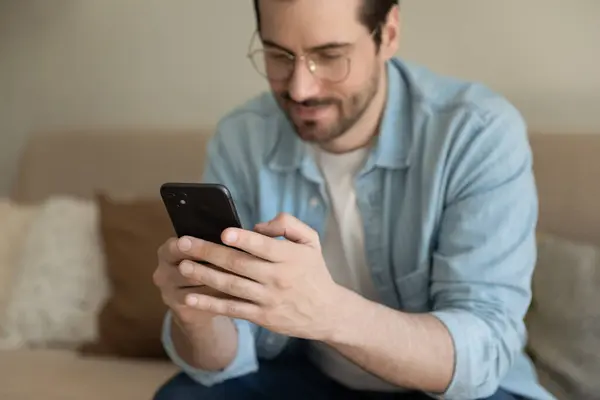 Millennial man texting on modern smartphone at home — Stock Photo, Image