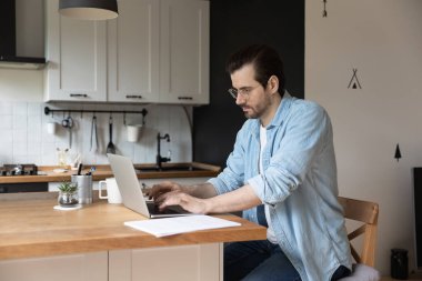 Ciddi bir adam bilgisayarla evden uzakta çalışıyor.