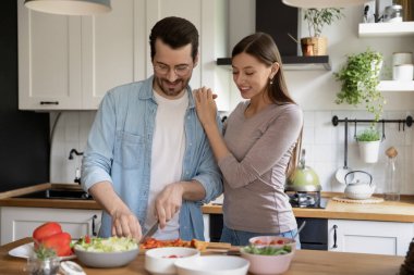 Mutlu milenyum çifti birlikte sağlıklı salata pişiriyor.