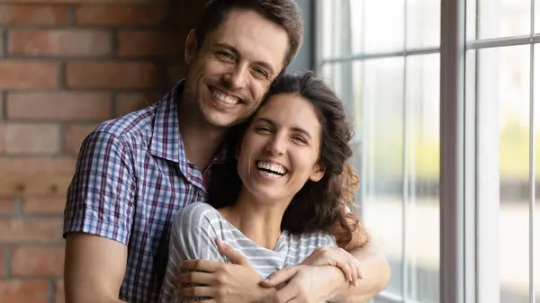 照片上的头像让年轻夫妇欣喜若狂，他们拥抱在一起，站在家里 — 图库照片