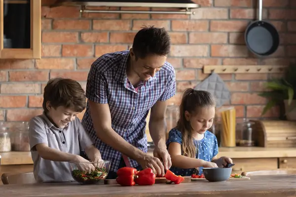Leende far med liten son och dotter matlagning sallad tillsammans — Stockfoto