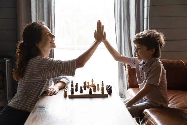 Sorrindo mãe e filho pequeno jogando xadrez, dando mais cinco — Fotografia de Stock