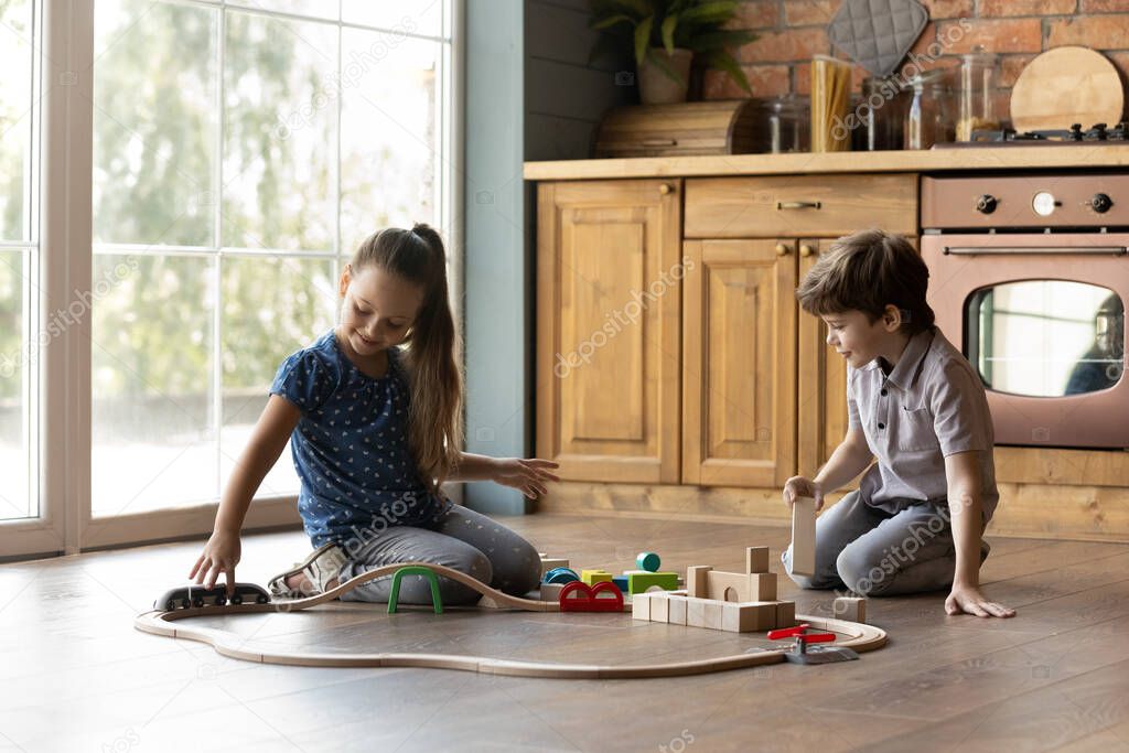 Two little kids playing with toys on warm floor