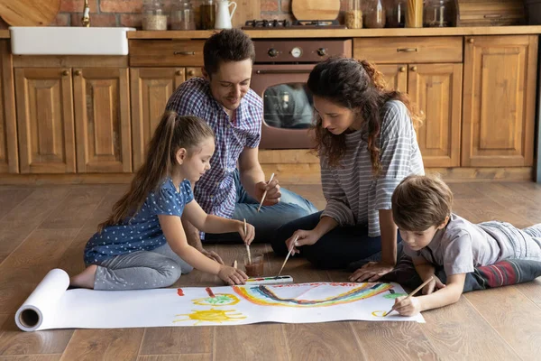 Glückliche Eltern mit zwei Kindern, die zusammen bunte Aquarelle malen — Stockfoto