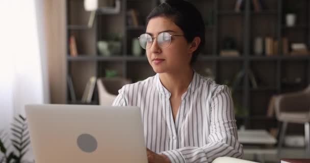 Счастливая индийская этническая женщина в очках, работающая за компьютером. — стоковое видео