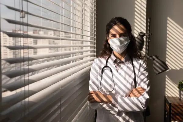Portrait confident female doctor wearing mask standing near window — Stock Photo, Image