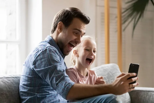 Emocionado papá y niña sentados en el sofá — Foto de Stock