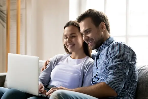 Happy young couple resting and hugging on sofa — Stock Photo, Image