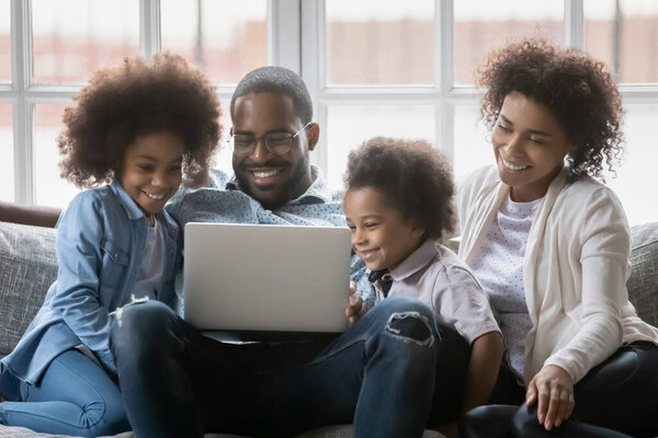 Happy African American couple and two kids relaxing on couch