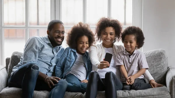 Heureux parents millénaires et enfants utilisant un smartphone — Photo