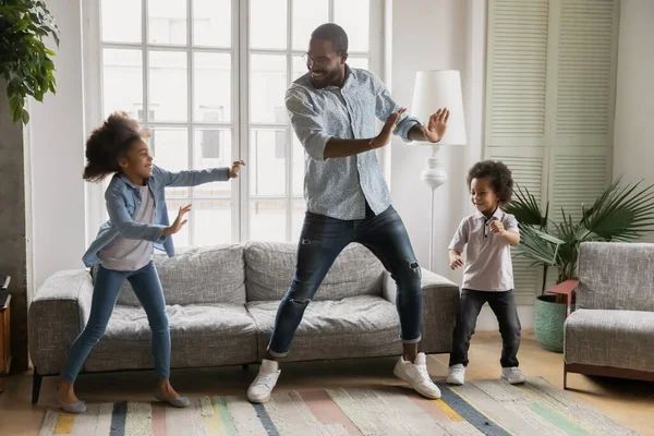 Szczęśliwy czarny tata uczy dzieci tańczyć w domu — Zdjęcie stockowe