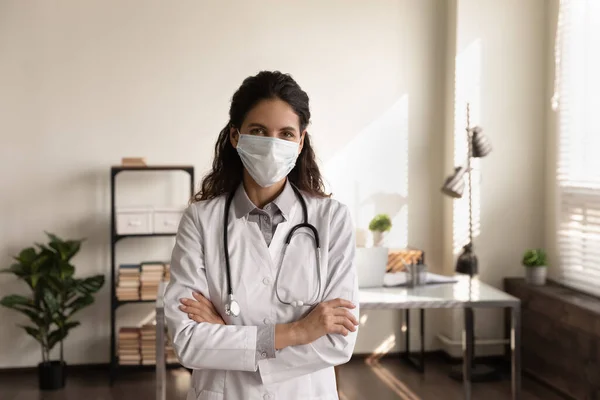 Porträtt professionell kvinnlig läkare bär medicinsk mask stående i ämbetet — Stockfoto