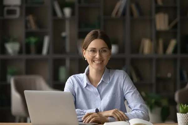 Улыбающаяся белая женщина работает за компьютером в офисе — стоковое фото