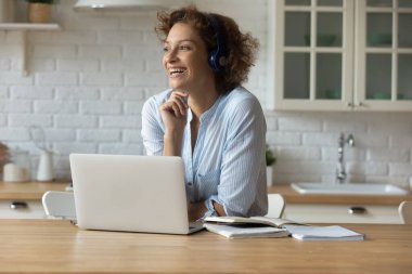 Kulaklıklı genç bayan mutfakta ders çalışmaktan dinleniyor.