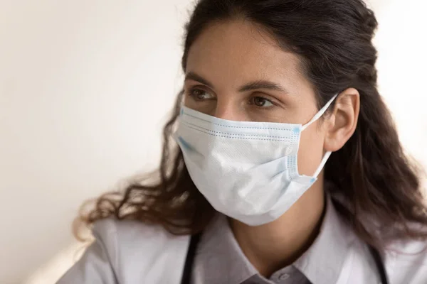 Zbliżyć się przemyślane kobieta lekarz noszenie medyczna maska twarz — Zdjęcie stockowe