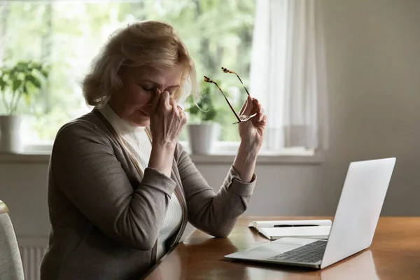 Mature 60s pensioner tired of using laptop at home — Stock Photo, Image