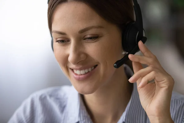 Close up de mulher branca sorridente em fones de ouvido trabalhando — Fotografia de Stock