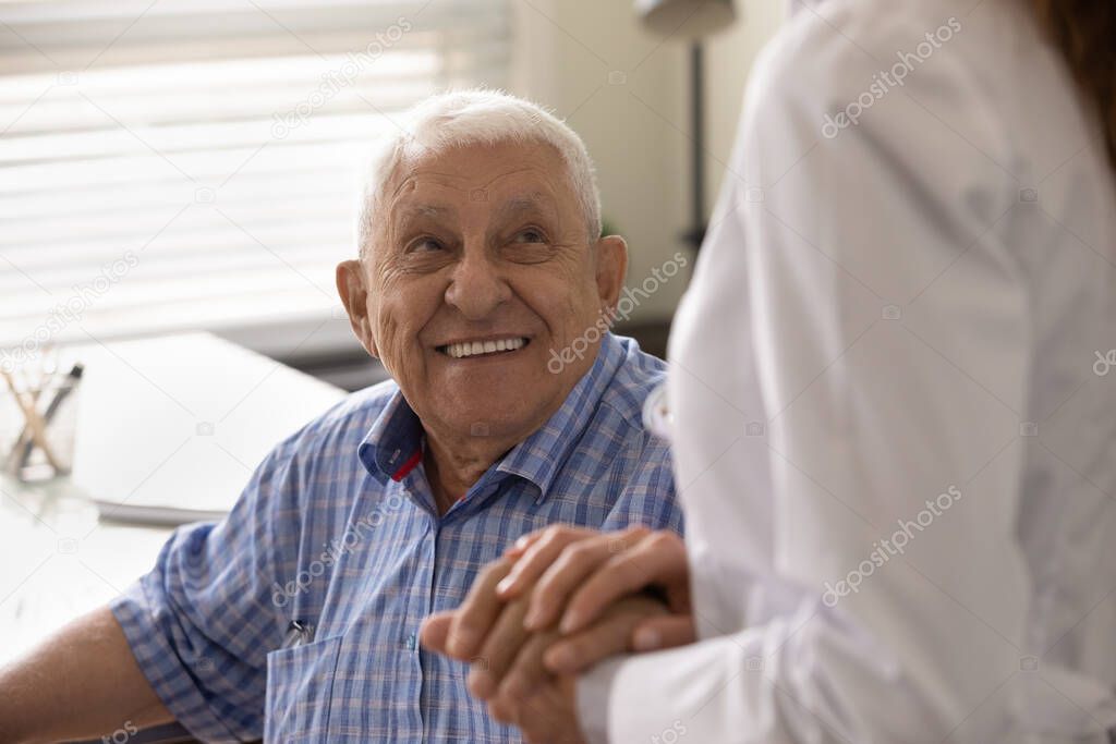 Close up smiling mature man and caregiver holding hands