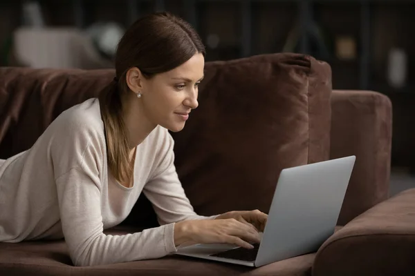 Giovane donna caucasica rilassarsi sul divano utilizzando laptop di lavoro — Foto Stock