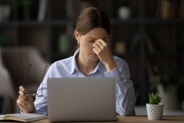 Dizüstü bilgisayarda çalışan yorgun kadın baş ağrısından muzdarip.