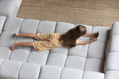 Kanepede uzanmış, hücreyi kullanan küçük bir kızın en iyi görüntüsü.